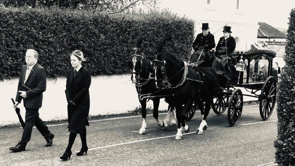 Carlyon funeral directors walking ahead of a horse-drawn hearse