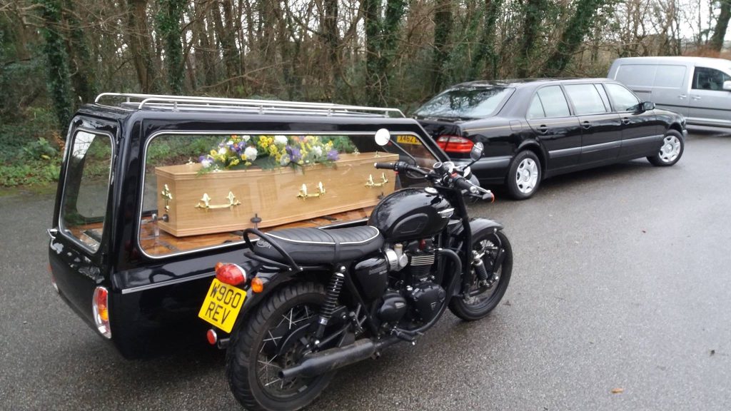 A motorbike hearse with a sidecar carrying a coffin and flowers